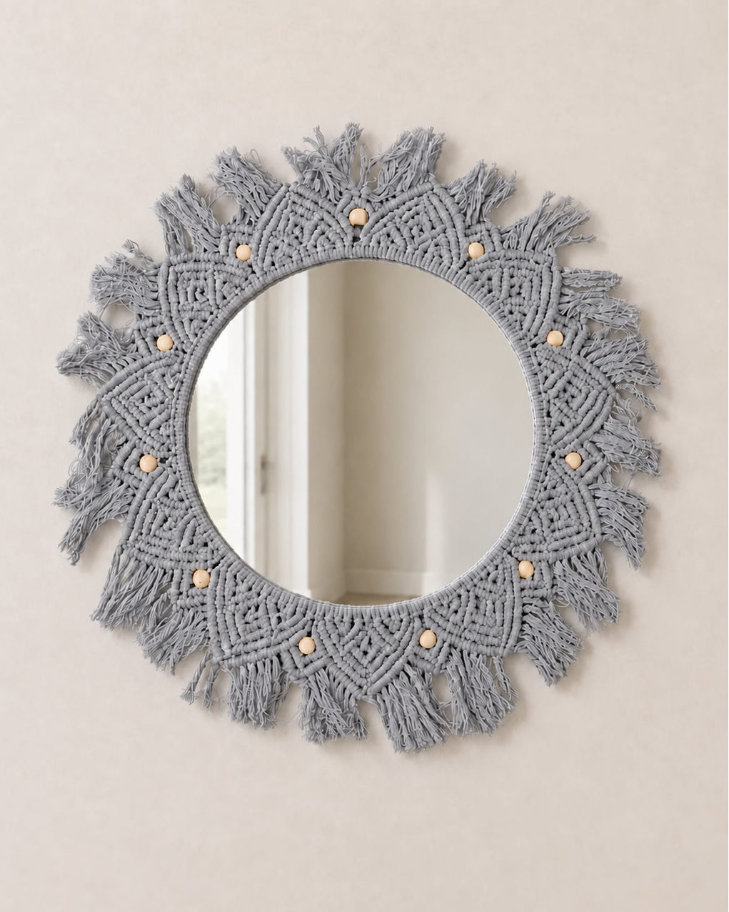 Round mirror with macrame frame on a beige wall