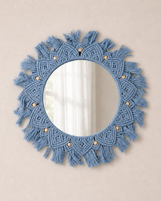 Round blue macrame mirror with tassels on a beige wall